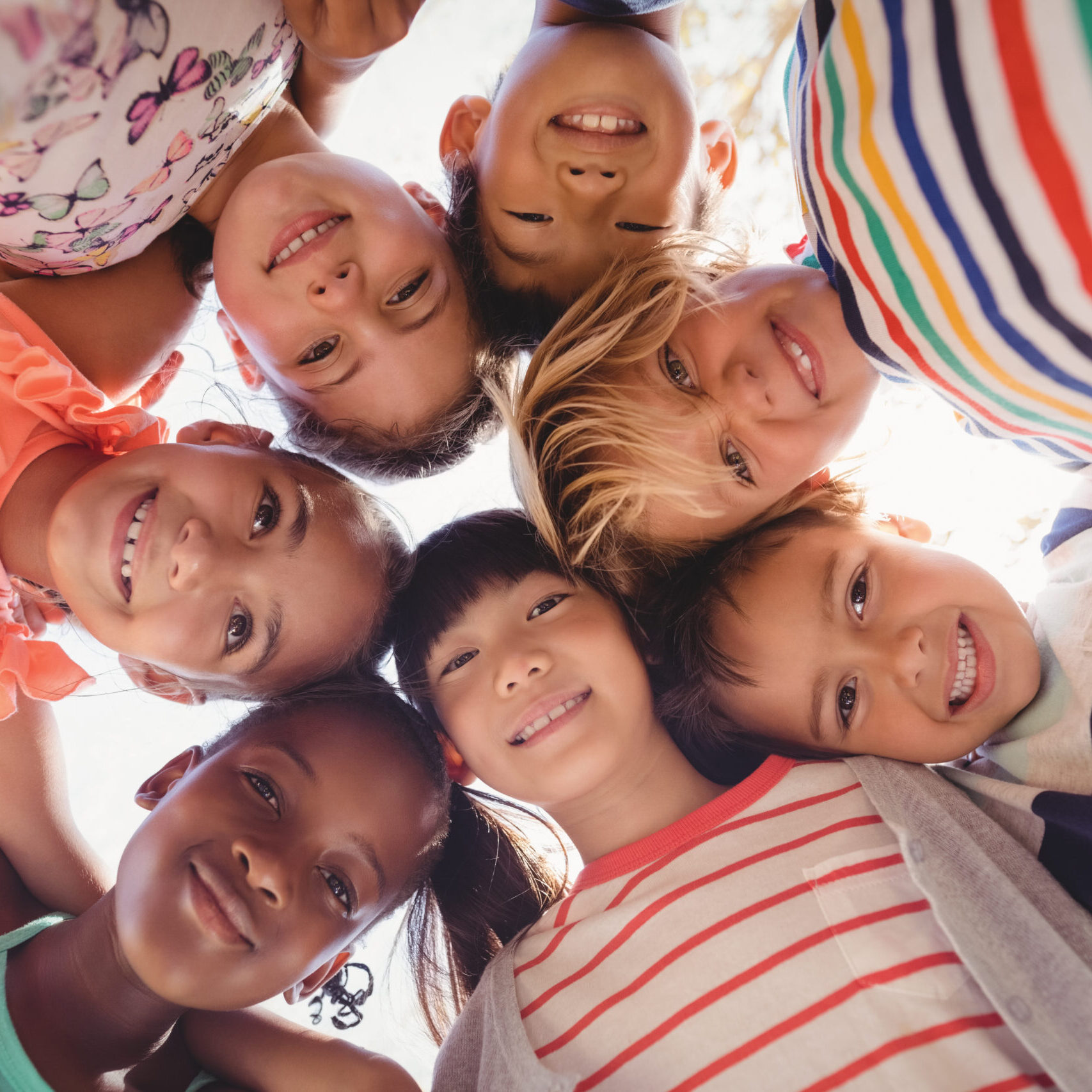 Portrait of schoolkids forming huddle on a sunny day